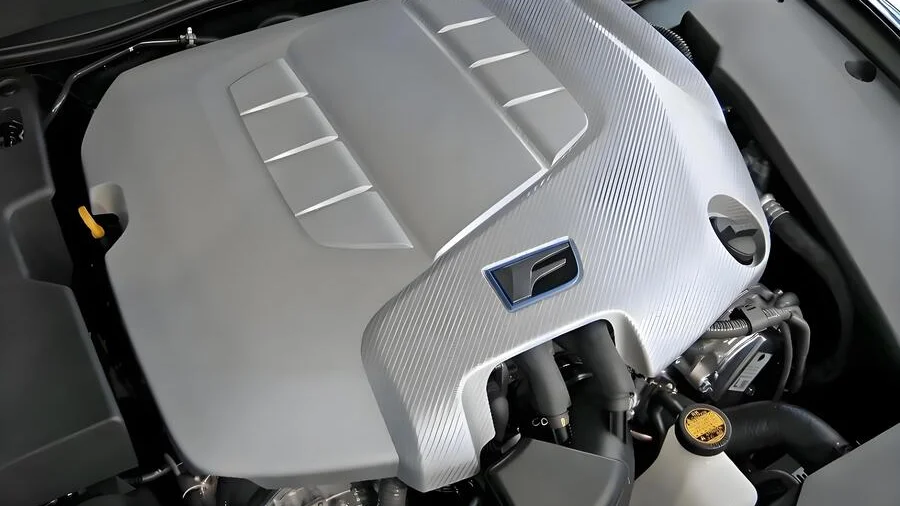 Close-up view of a silver car engine cover with a textured surface and brand logo.