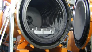 Interior view of a large industrial vacuum chamber with concentric grooves and metallic components.