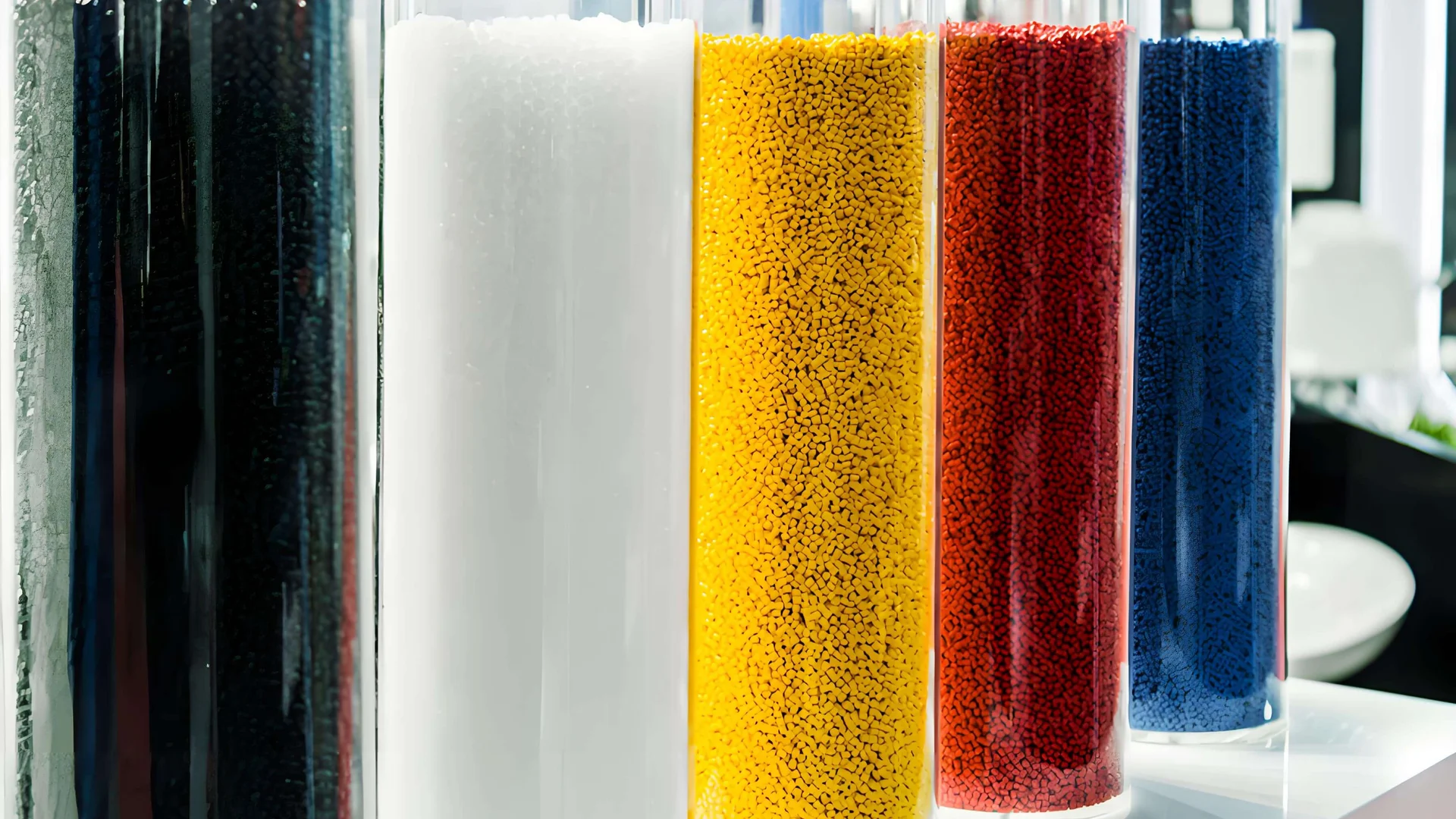 Reihe transparenter Behälter, gefüllt mit schwarzen, weißen, gelben, roten und blauen Materialien