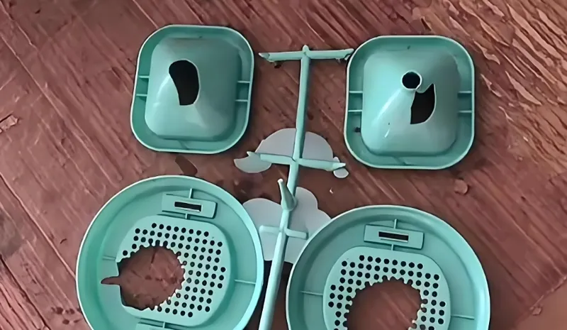 Disassembled plastic strainer with multiple components on a wooden surface