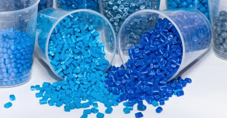 Various shades of blue plastic pellets spilling from cups.