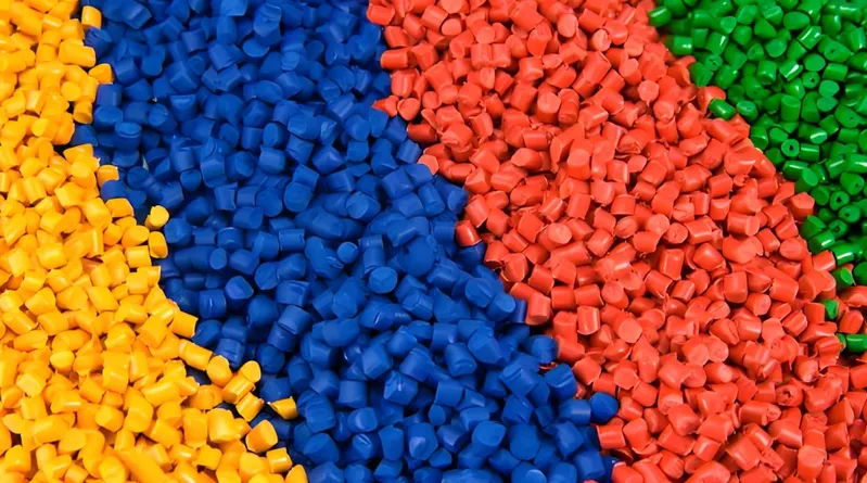An assortment of brightly colored plastic pellets in yellow, blue, red, and green.
