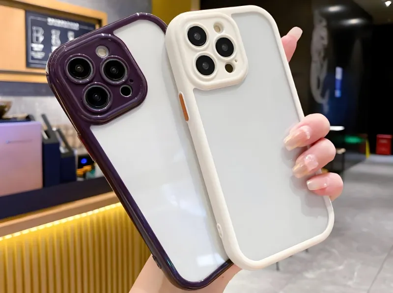 A person holding two smartphones, each in a different colored protective case, inside a modern interior