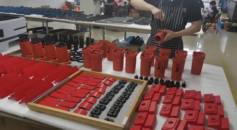 Person assembling parts in a factory with tables full of red and black components