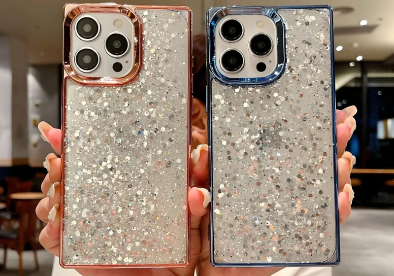 Two hands holding smartphones with glittery cases in a room