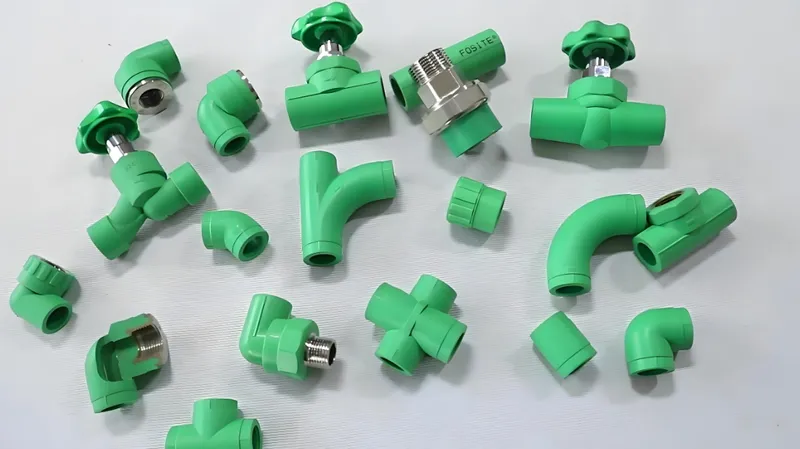 Assorted green plastic plumbing pipe fittings and valves on a light background