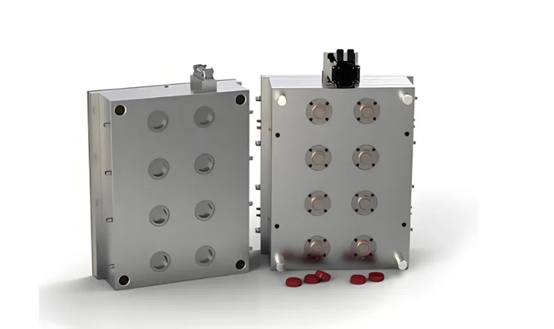 A metallic injection mold with cavities used for manufacturing parts, with red objects in front