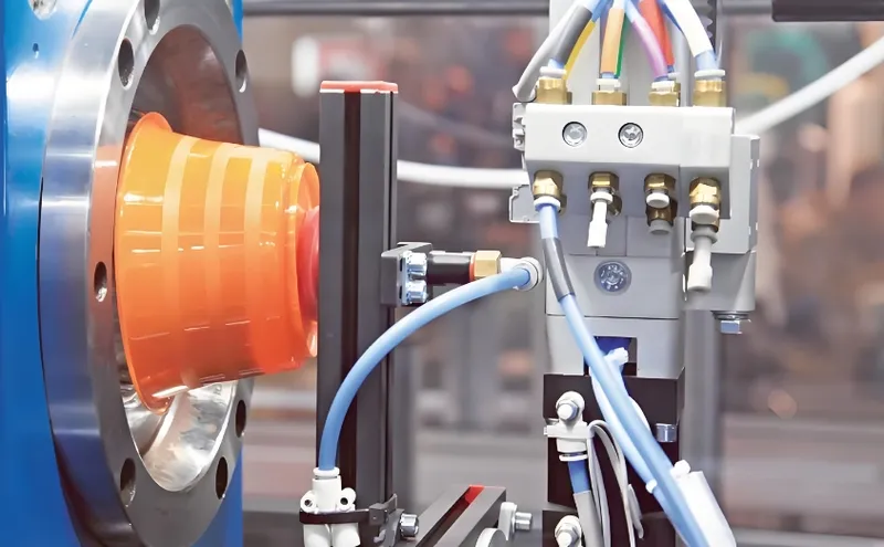 Close-up of an injection molding machine with orange and blue components