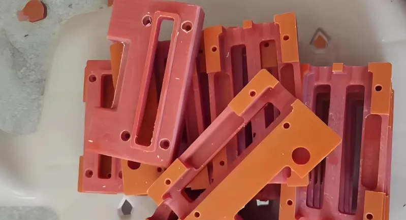 A collection of red plastic injection molded parts with various slots and holes, stacked together