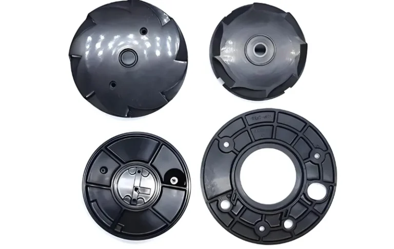 Four black plastic impellers and volute casings for pump use arranged in a grid formation.