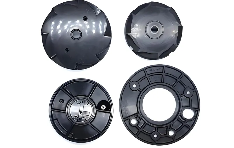 Four black plastic impellers and volute casings for pump use arranged in a grid formation.