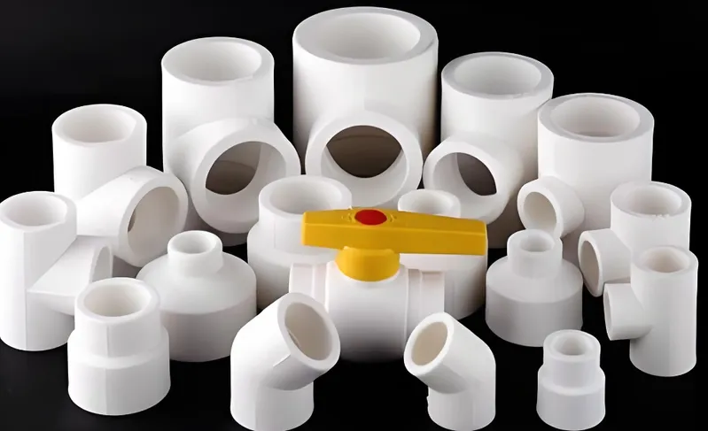 A variety of white PVC pipe fittings arranged with a yellow valve in the center