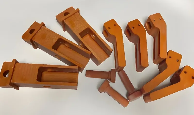An assortment of orange wooden blocks and cylindrical pegs laid out on a white surface