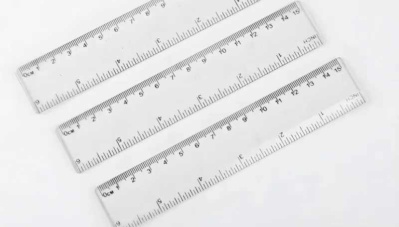 Three clear plastic rulers marked with centimeters and inches on a white background.