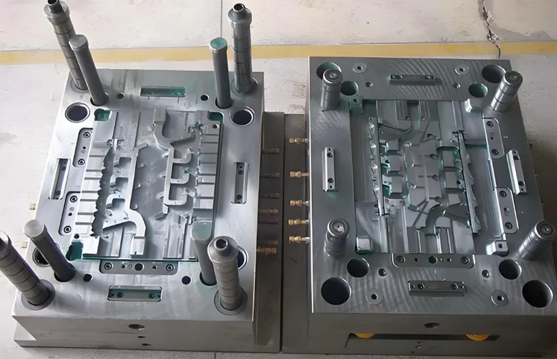 A photo of a plastic injection mold with two halves showing detailed metalwork and components