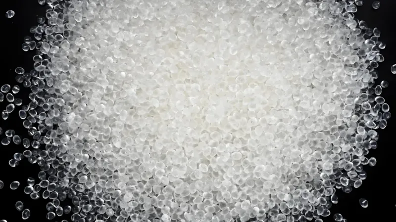 A pile of clear plastic pellets on a dark surface