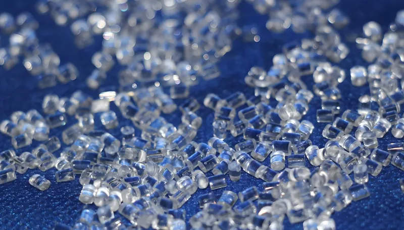 青い表面に散らばった透明なプラスチックペレットのクローズアップビュー。