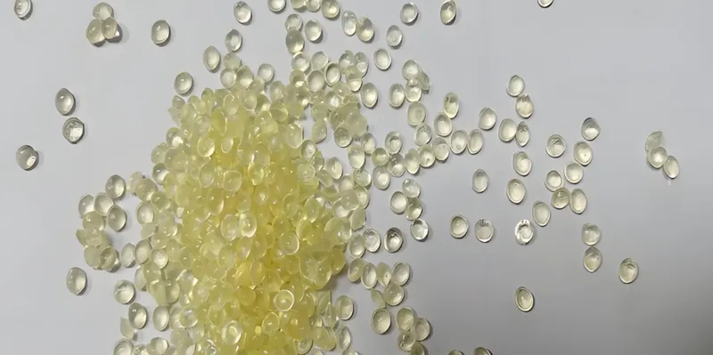 A pile of small yellow resin pellets scattered on a white surface