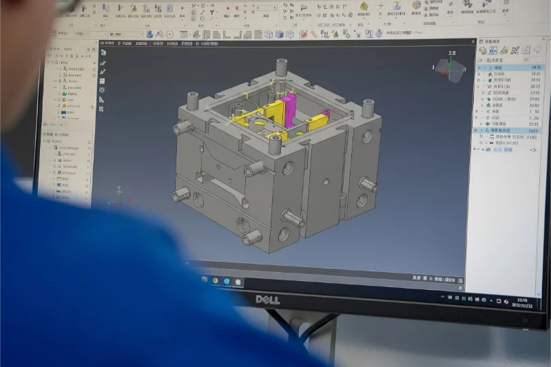 CAD সফটওয়্যার ব্যবহার করে একজন ব্যক্তি একটি ইনজেকশন ছাঁচের 3D নকশা প্রদর্শন করছেন, যেখানে ছাঁচের গঠন এবং উপাদানগুলি বিস্তারিতভাবে দেখানো হচ্ছে।